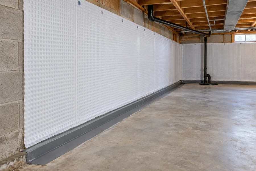 White drainage membrane fitted across basement block walls above a perimeter drainage channel.